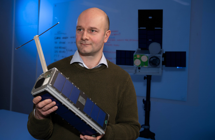 Dr Melrose Brown holds a cubesat at UNSW Canberra.